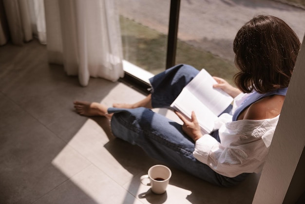 Punto di vista completo della donna che esamina il libro al piano di casa