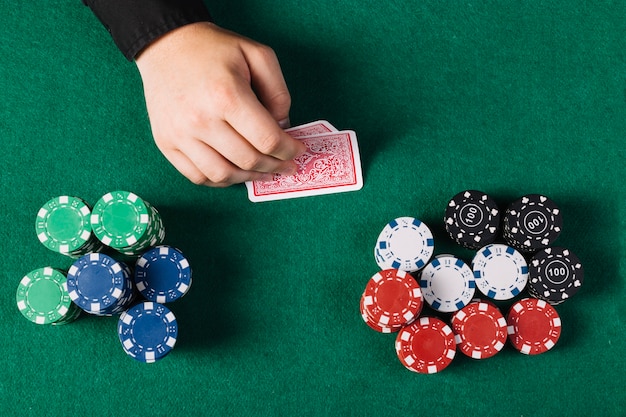 Punto di vista dell&#39;angolo alto della mano del giocatore con le carte da gioco vicino al tavolo da poker