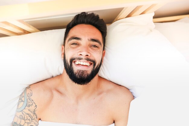 Punto di vista dell&#39;angolo alto di un uomo sorridente che si trova sul letto