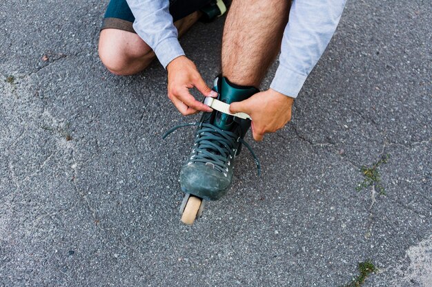 Punto di vista elevato della mano di un uomo che mette sui rollerskate