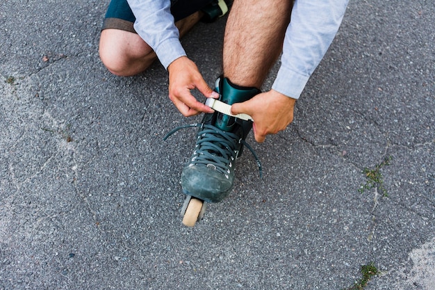 Punto di vista elevato della mano di un uomo che mette sui rollerskate