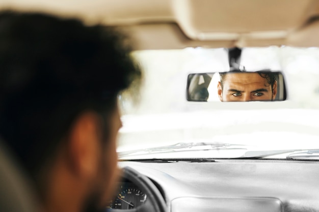 Punto di vista posteriore dell'uomo che controlla lo specchio di automobile