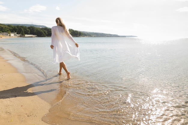 Punto di vista posteriore della donna che gode delle sabbie della spiaggia