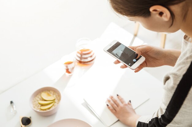 Punto di vista posteriore della donna che prende le immagini moderne sul telefono.