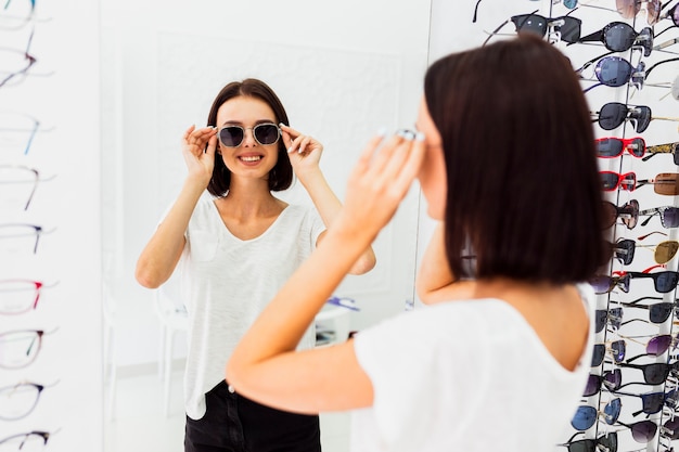 Punto di vista posteriore della donna che prova gli occhiali da sole