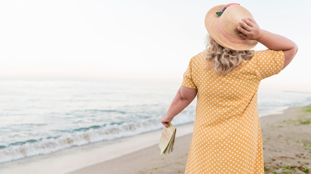 Punto di vista posteriore della donna turistica più anziana alla spiaggia