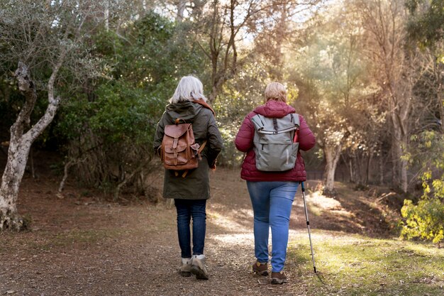 Punto di vista posteriore delle donne anziane che godono di una passeggiata nella natura
