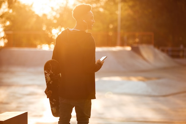 Punto di vista posteriore di un adolescente maschio africano sorridente con le cuffie