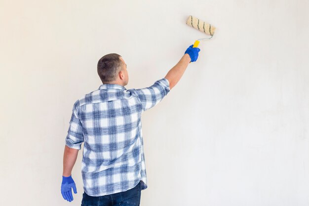 Punto di vista posteriore di un lavoratore con lo spazio della copia del rullo di pittura