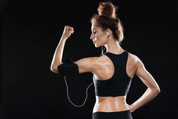 Punto di vista posteriore di una donna di forma fisica che mostra il suo bicipite