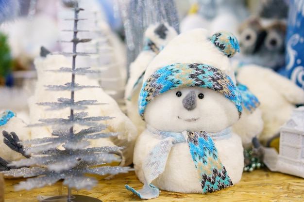 Pupazzo di neve bianco giocattolo decorazione natalizia fatto di cotone idrofilo con una sciarpa blu, sullo scaffale del negozio