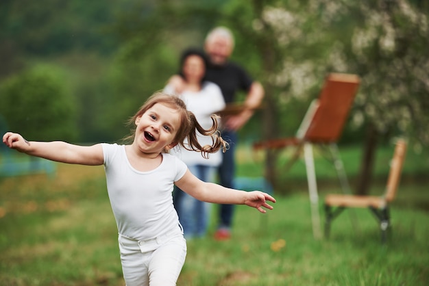 Pura felicità. Nonna e nonno si divertono all'aperto con la nipote. Concezione della pittura