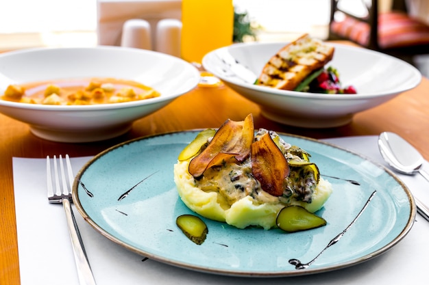 Purè di patate con melanzane fritte, sottaceti e salsa di panna su un piatto