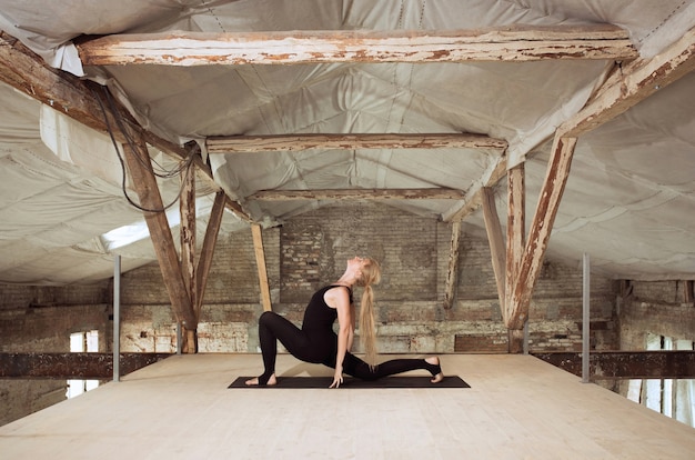 Purezza. Una giovane donna atletica esercita lo yoga su un edificio abbandonato. Equilibrio della salute mentale e fisica. Concetto di stile di vita sano, sport, attività, perdita di peso, concentrazione.