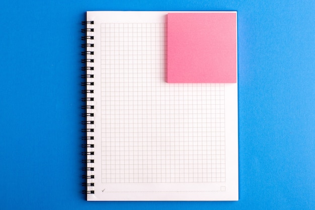 Quaderno aperto vista frontale con adesivo rosa sulla scrivania blu