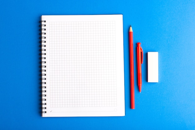 Quaderno aperto vista frontale con matita su superficie blu