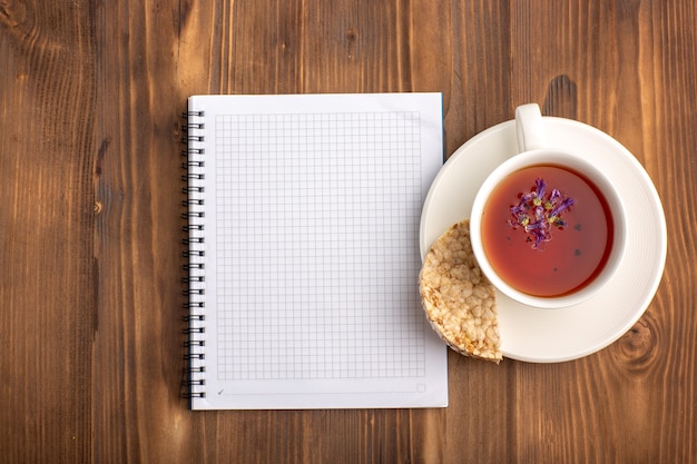 Quaderno blu aperto vista dall'alto con una tazza di tè sulla scrivania marrone