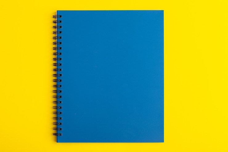 Foto gratuito quaderno blu aperto vista frontale sullo scrittorio giallo