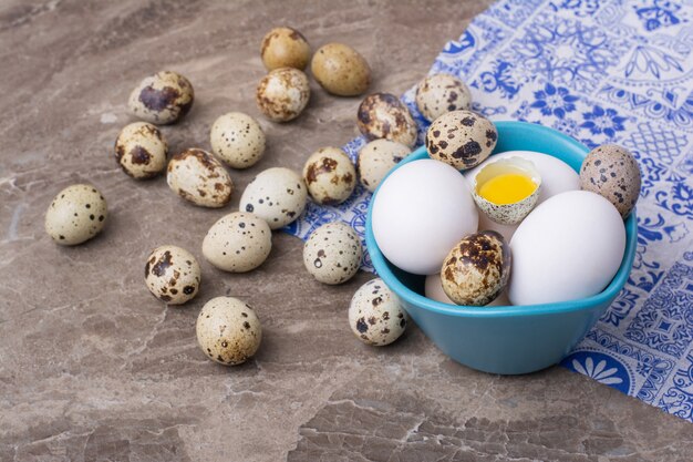 Quaglia e uova di gallina in una tazza blu