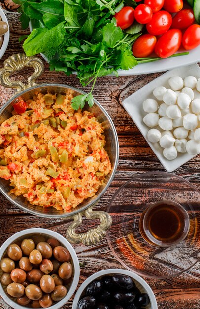 Qualche pasto delizioso con una tazza di tè, insalata, sottaceti in un piatto su superficie di legno, vista dall'alto