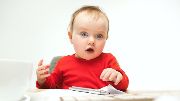 Quanti documenti posso firmare bambina bambino seduto con la tastiera del moderno computer o laptop in studio bianco.