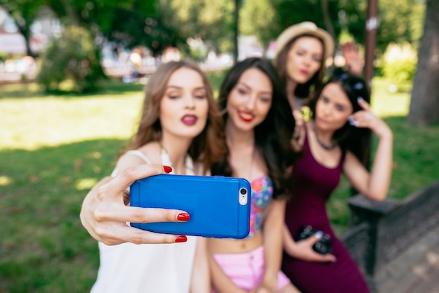 Quattro belle giovani donne fanno selfie nel parco