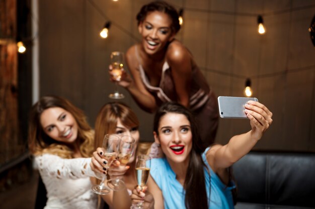 Quattro belle ragazze che fanno selfie alla festa.