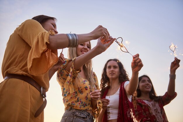 Quattro giovani donne con stelle filanti accese durante il tramonto