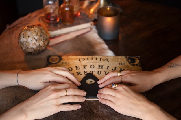 Quattro mani usando la tavola Ouija ad angolo alto