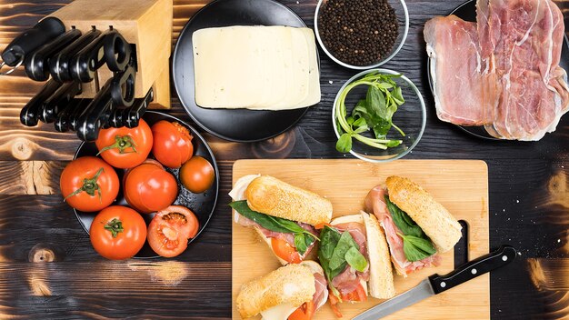 Quattro panini sul tavolo della cucina circondati dagli ingredienti di cui sono fatti