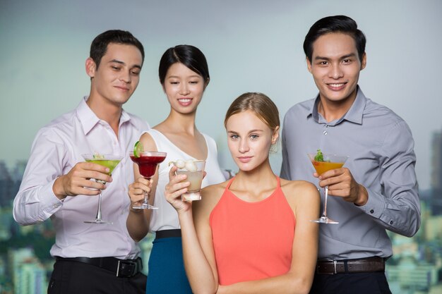 Quattro sorridenti giovani in possesso di un cocktail nel bar