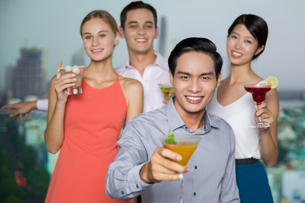 Quattro sorridenti uomini e donne con cocktail a Party