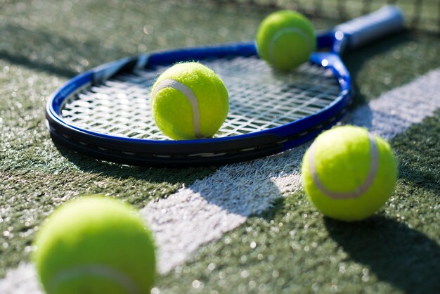 Racchetta da tennis del primo piano e palle sulla terra