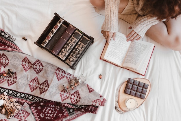 Raccolga il libro di lettura della donna vicino a cioccolato