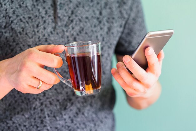 Raccolga la bevanda e lo smartphone della tenuta dell&#39;uomo