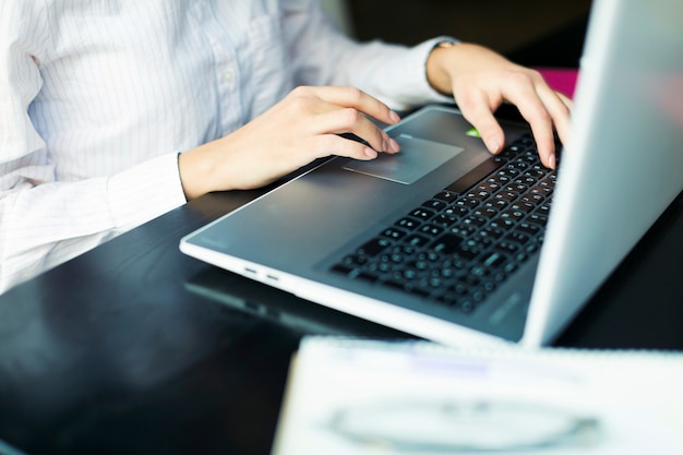 Raccolga la donna che per mezzo del computer portatile alla tavola