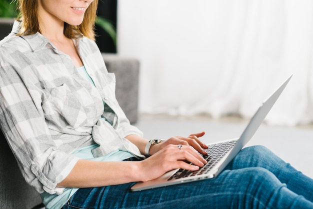 Raccolga la donna che per mezzo del computer portatile vicino allo strato