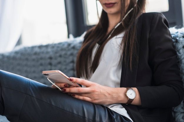 Raccolga la donna che per mezzo dello smartphone sul sofà