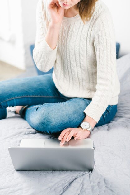 Raccolga la donna con il computer portatile sul letto