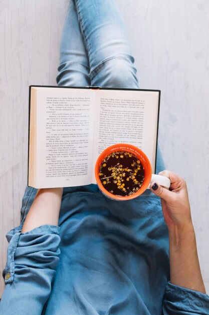 Raccolga la donna con il libro di lettura del tè