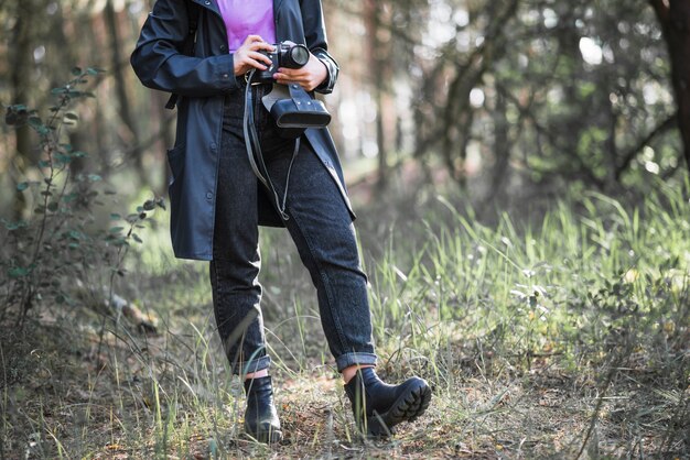Raccolga la donna con la macchina fotografica in foresta