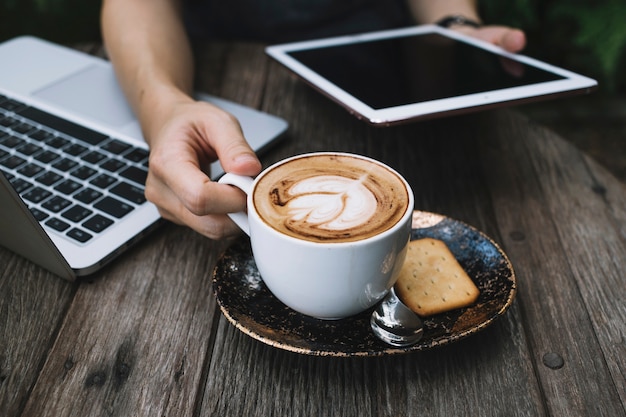 Raccolga la persona con la compressa che beve il caffè