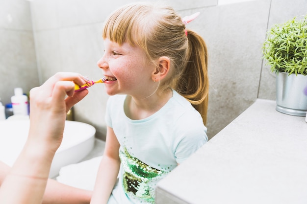 Raccolga madre che pulisce i denti della figlia