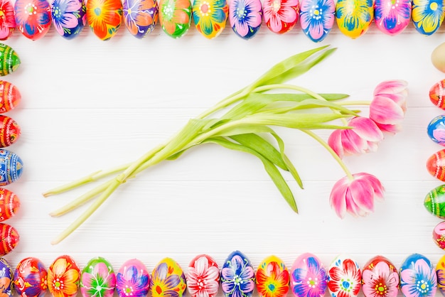 Raccolta di uova colorate su bordi e fiori