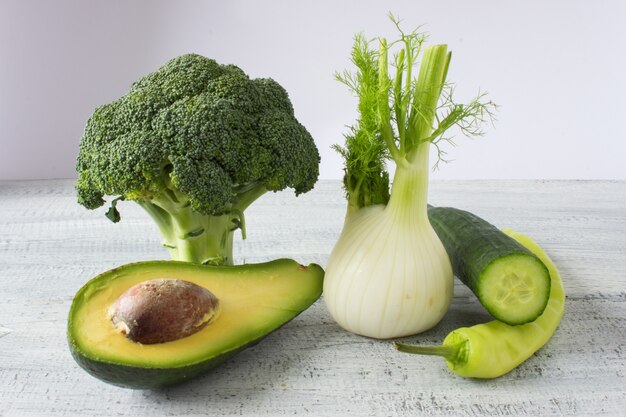 Raccolta di verdure fresche su sfondo bianco rustico, broccoli, finocchio, avocado, cetriolo, pepe