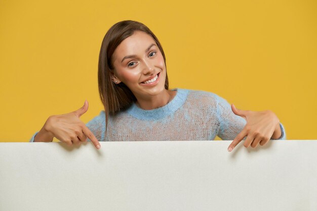 Raccolto di ragazza sorridente che punta al foglio di carta