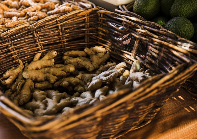 Radici fresche dello zenzero in canestro di vimini marrone al mercato della drogheria