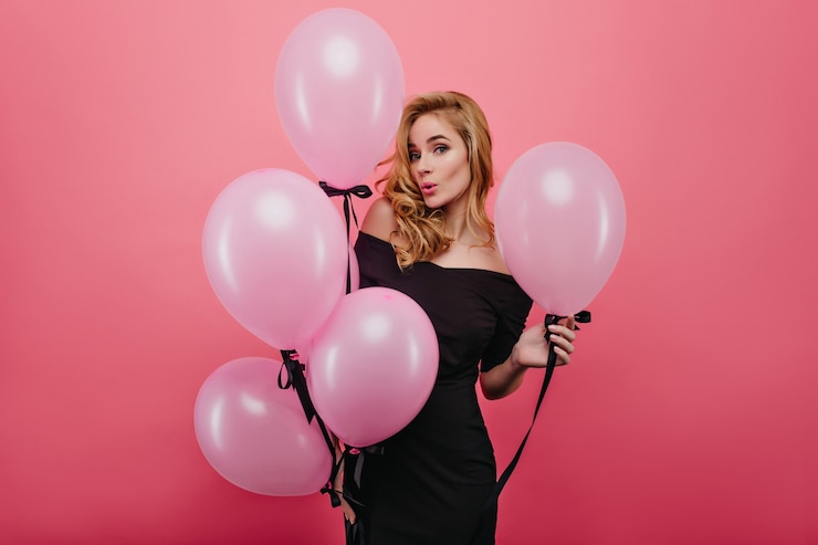 Foto gratuito raffinata donna bianca con palloncini in posa con l'espressione del viso sorpreso. ritratto di attraente ragazza riccia in attesa per la festa di compleanno.