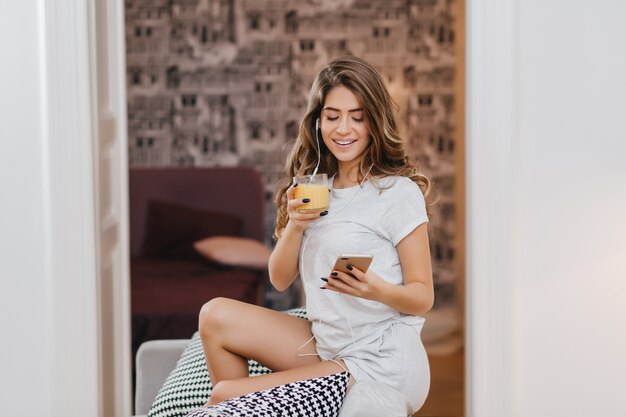 Raffinata giovane donna con un bicchiere di succo di frutta in posa nella sua stanza