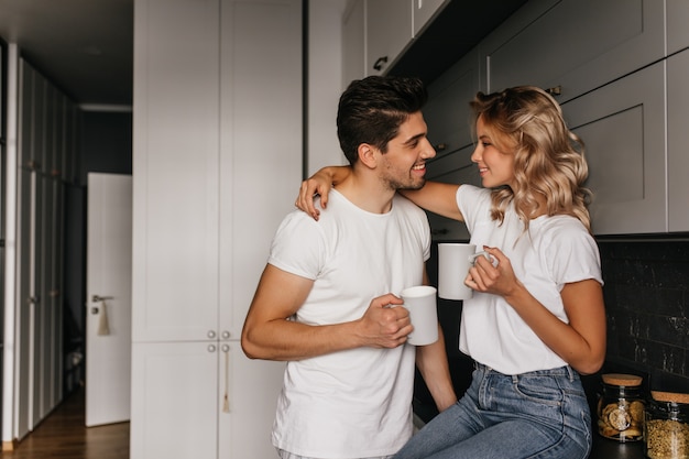 Raffinata ragazza che beve caffè con il marito. Coppia rilassata agghiacciante in cucina mattina.